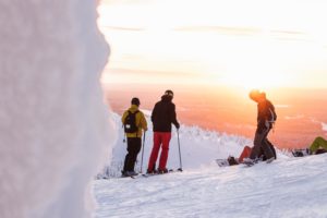 Skid- och snowboardåkare iakttar solnedgången från skidbacken
