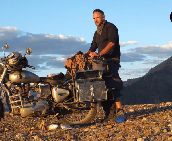 eYo-Eyewear-Ambassador und Shades of Love-Gründer Jürgen Altmann steht vor einem Motorrad im Himalaya.